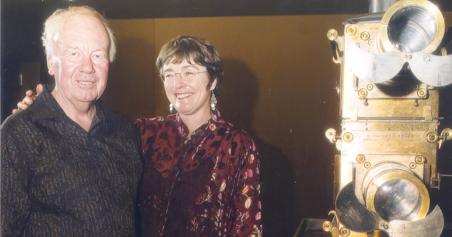 Two curators beside a historic brass projection lantern.
